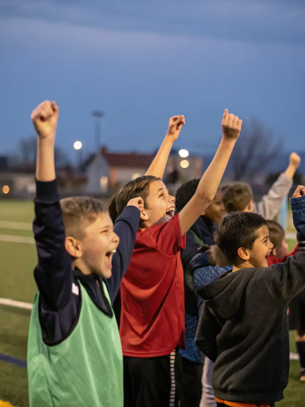 A vibrant image of young football players in CLUB ECOLE PYRENEES ARIEGEOISES FOOTBALL uniform, celebrating a goal during a match, showcasing their teamwork and joy.